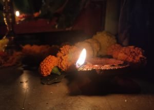 Lit clay diya lamp surrounded by marigold flowers for Diwali