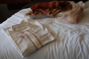 Ivory embroidered cotton kurta pajama set for men, folded on a bed
